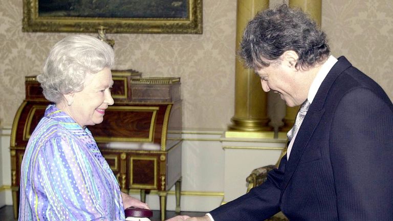 Kraliçe II. Elizabeth, 2000 yılında Liyakat Nişanı Üyesi nişanını kendisine sunmadan önce Sör Tom'un elini sıkıyor. Dosya resmi: PA