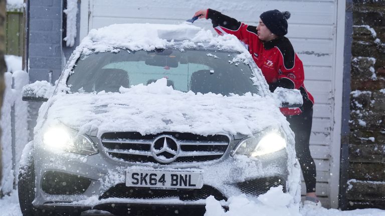 County Durham'daki Tow Law'da arabasındaki karı temizleyen bir kişi. Resim: PA
