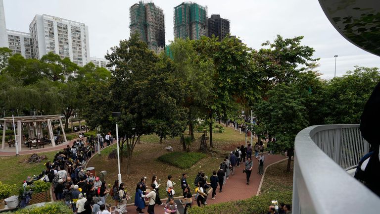 People line up to offer flowers and prayers for the victims of the fire at Wang Fuk Court. Pic: AP