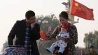 A couple takes pictures with their baby on the Tiananmen Gate in Beijing November 2, 2015. China must continue to enforce its one-child poli
