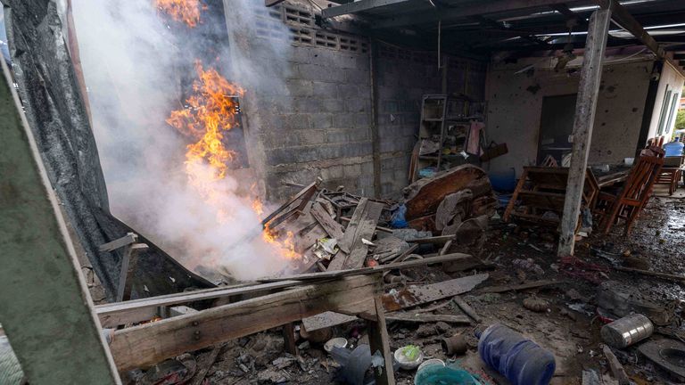 Flame rises from a house which, Thai local security forces say, was damaged by a Cambodian artillery strike in Surin province, Thailand, on 11 December. Pic: AP
