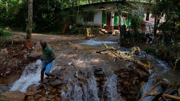Osoba, która przeżyła osuwisko, przecina odcinek uszkodzonej drogi w wiosce Sarasavigama w pobliżu Kandy na Sri Lance. Zdjęcie: AP