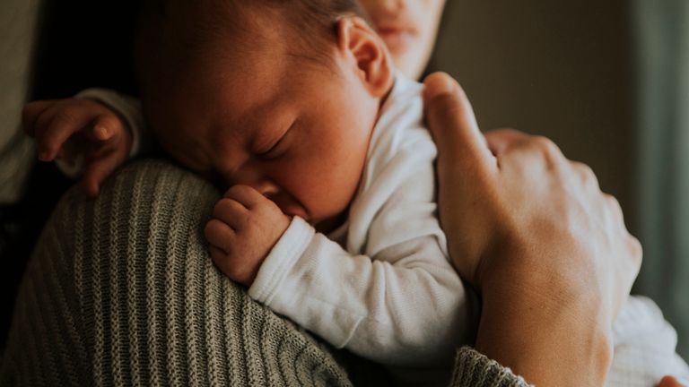 Mother holding her baby indoors stock photo