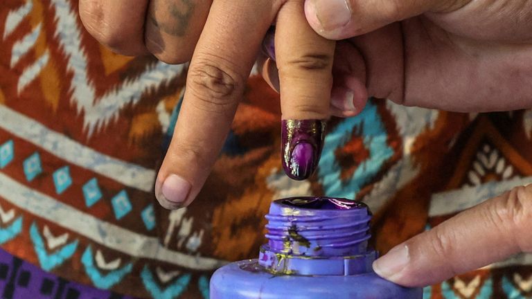 A polling official assists a woman during voting at a polling station. Pic: Reuters