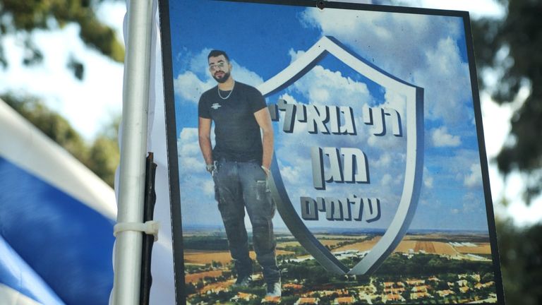 這張海報將 Ran Gvili 描述為“Alumim 之盾”，基布茲將保護他們的功勞歸功於他和他的團隊