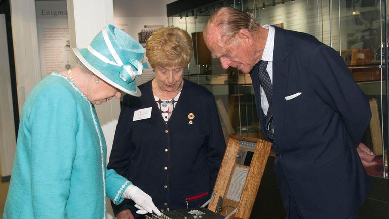 Ruth Bourne, Queen Elizabeth II and Prince Philip examine a World War II German Enigma encoding machine on 15 July, 2011. Pic: AP