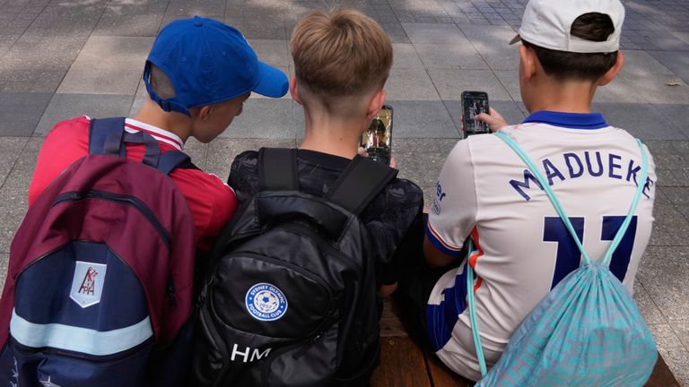 Australian schoolboys use their phones while sitting outside a school in Sydney. Pic: AP