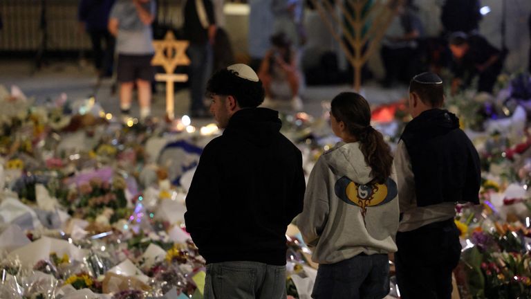People look at flowers laid out for the victims. Pic: Reuters