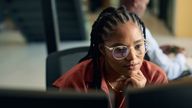 Young woman programmer focused on her work, coding on dual monitors in a modern office environment stock photo