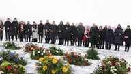 27 January 2026, Thuringia, Weimar: Participants stand at a memorial plaque during a wreath-laying ceremony to mark the Day of the Victims of National Socialism at the former Buchenwald concentration camp This day has been celebrated in Germany since 1996 at the suggestion of the then Federal President Roman Herzog. On January 27, 1945, the Auschwitz concentration camp was liberated by Soviet troops.