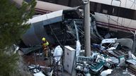 A firefighter and members of the Spanish Civil Guard work next to one of the trains involved in the accident, at the site of a deadly derail