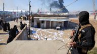 A member of the Syrian government security forces stands guard as a group of detainees gather at al-Hol camp after the government took contr