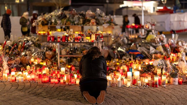 A woman lights a candle at a memorial outside the Le Constellation bar. Pic: Reuters 