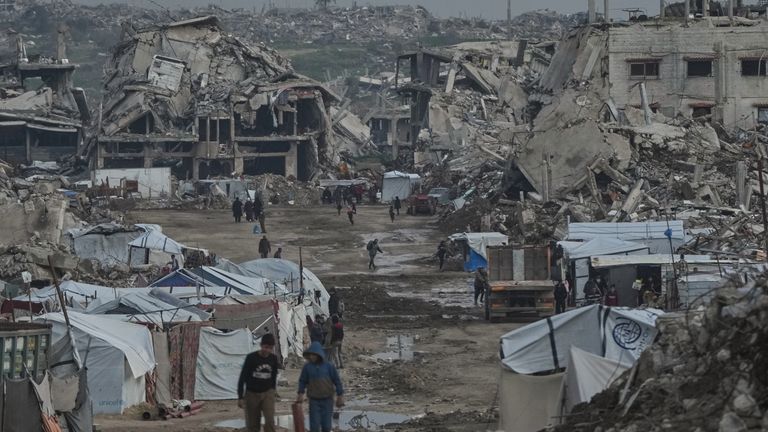 Palestinos caminham entre edifícios destruídos pelas operações aéreas e terrestres israelenses em Gaza. Foto: AP