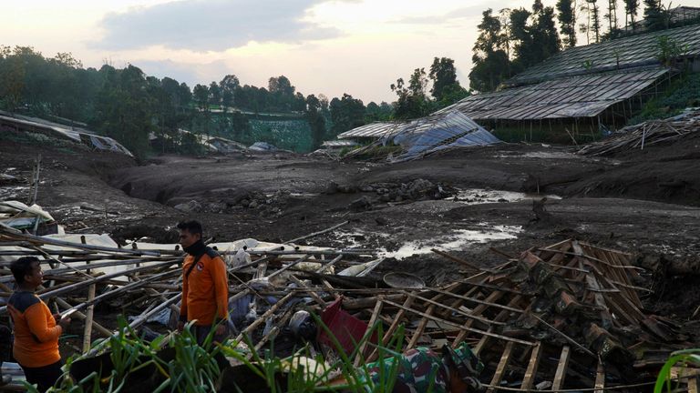 Rescue workers stand near damaged houses. Pic: Reuters