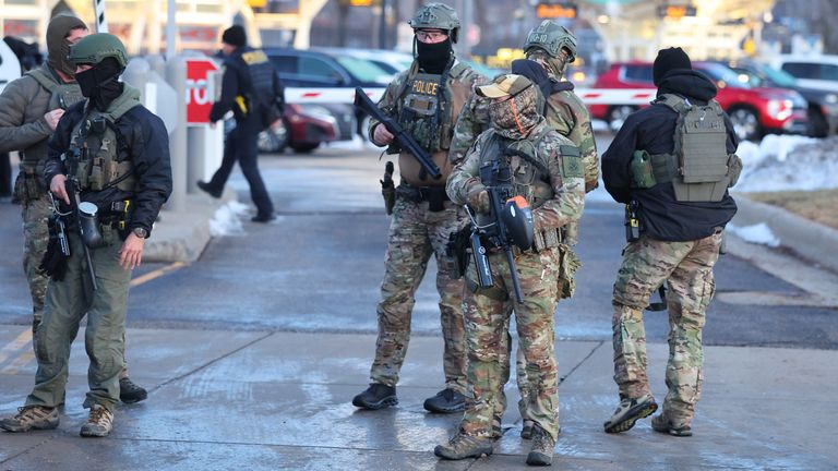 Federal agents stand outside a federal building as protesters gather in Minneapolis. Pic: AP