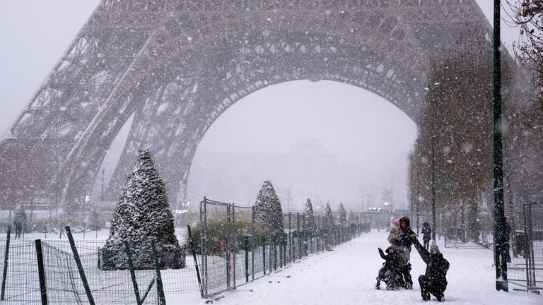 People walk near the Eiffel Tower during snowfall on Wednesday. Pic: AP Photo/Christophe Ena.