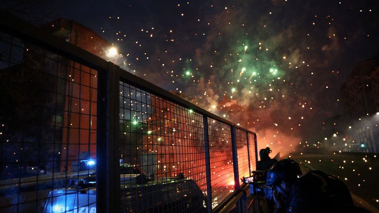 Fogos de artifício explodem no céu acima dos policiais. Foto: Reuters
