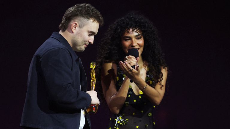 Sam Fender on stage with Olivia Dean, accepting the song of the year award. Pic: Reuters