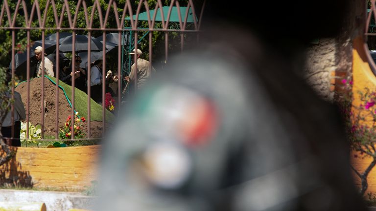 Mourners used umbrellas to block the view of the casket. Pic: Reuters
