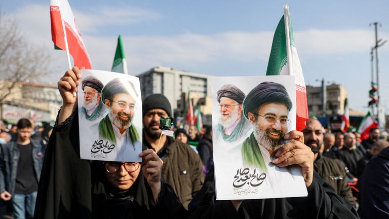 People hold placards with an image of Mojtaba Khamenei in Tehran. Pic: WANNA/Reuters