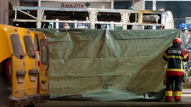 Firefighters and police officers install barriers to secure the area where a postal bus caught fire in Kerzers. Pic: AP