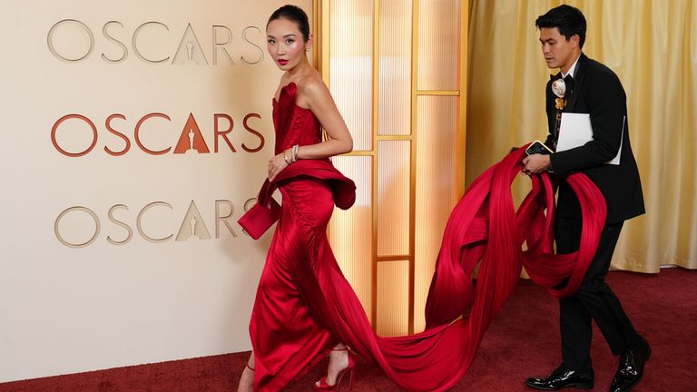 Sinners star Li Jun Li, stuns in red, with a little help to manage her epic train. Pic: AP