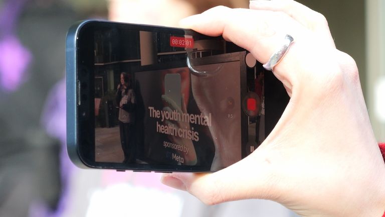 Bir izleyici, Mad Youth Organize'den Hannah'nın protesto sırasında konuşmasını izliyor