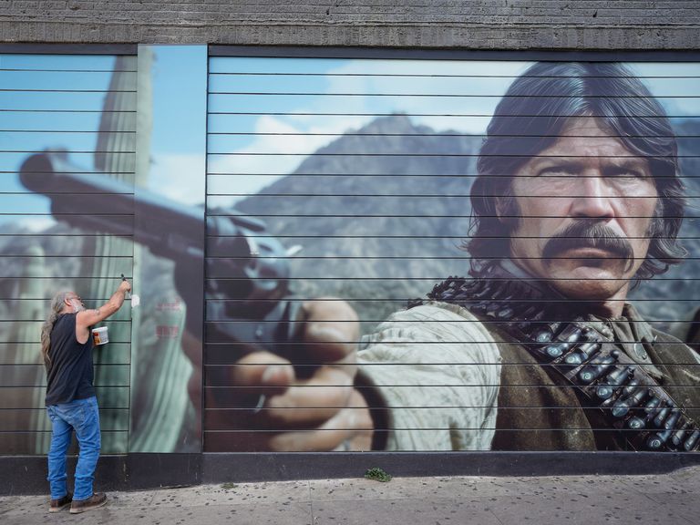 A bar worker repairs a bullet hole on West 6th Street, Austin on Monday - the day after the mass shooting in the city's entertainment district. Pic: AP