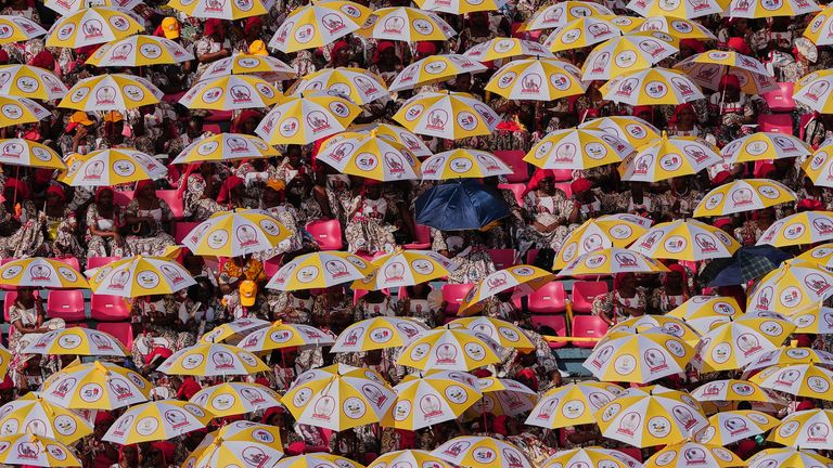 People sit holding umbrellas as they wait to see Pope Leo XIV at Estadio de Bata Stadium, in Bata, Equatorial Guinea. Pic: AP