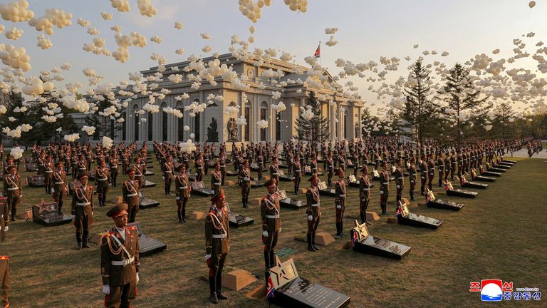 Balloons fly as soldiers stand in position next to memorial stones. Pic: KCNA/Reuters