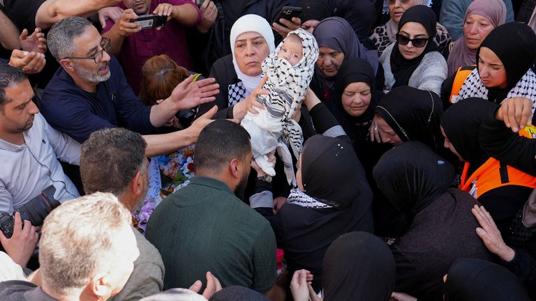 Mourners hold aloft one of Mr Awawdeh's twins at the funeral procession. Pic: Reuters