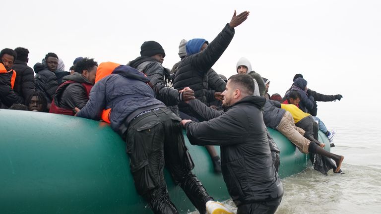 Migrants struggle to board a small boat off the coast of France. Pic: PA