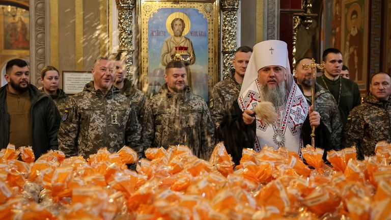 Head of Ukraine's Orthodox church sprinkling holy water on Easter cakes for troops. Pic: Reuters
