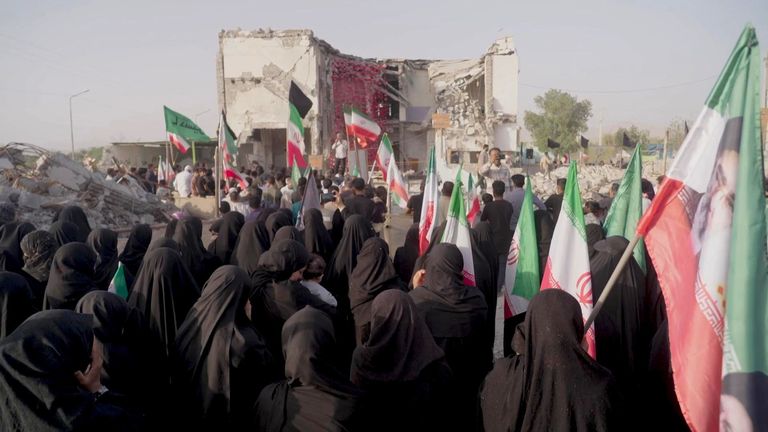 People gather at the ruins of the school