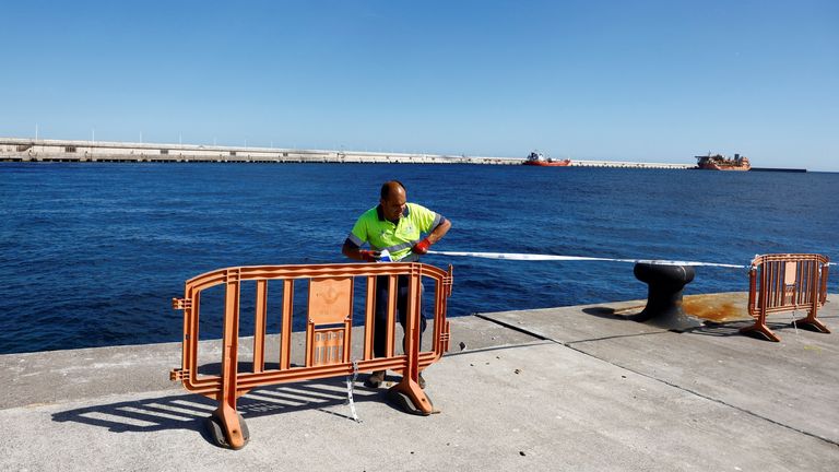 A worker cordons off the area at the port where ship will dock. Pic: Reuters