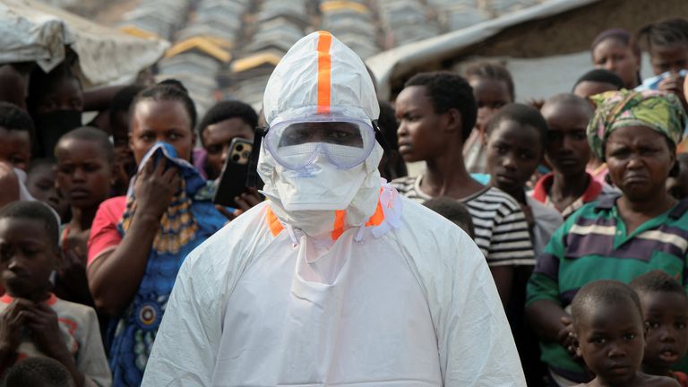 Health worker stands near displaced people waiting for the burial at Kigonze. Pic: Reuters
