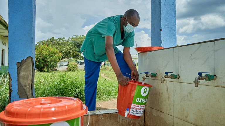 Emmanuel Bahiga setting up bucket with tap as part of hygiene measures at the Rwampara General Referral Hospital. Pic: Oxfam