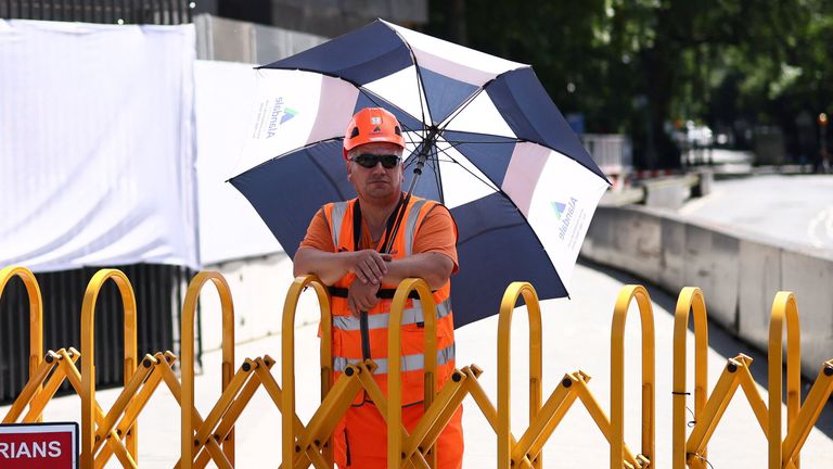 A worker in London uses an umbrella as a shield against the sun as a heatwave grips the UK. Pic: Reuters