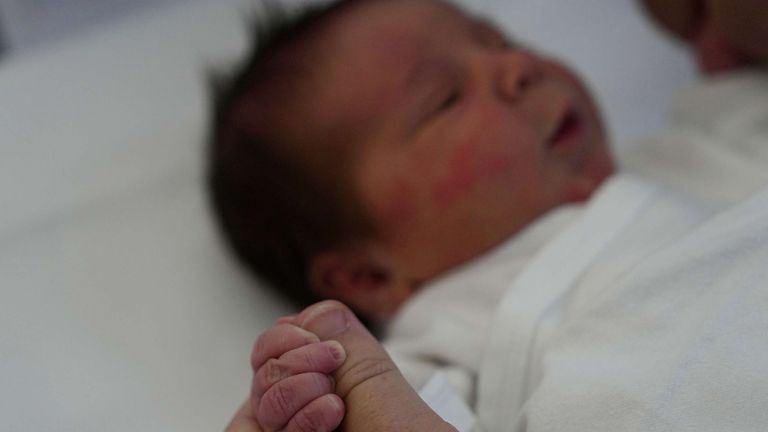 Cristina Rapti-Tzelepi, holds the hand of her three-day-old daughter, Georgia. Pic: AP