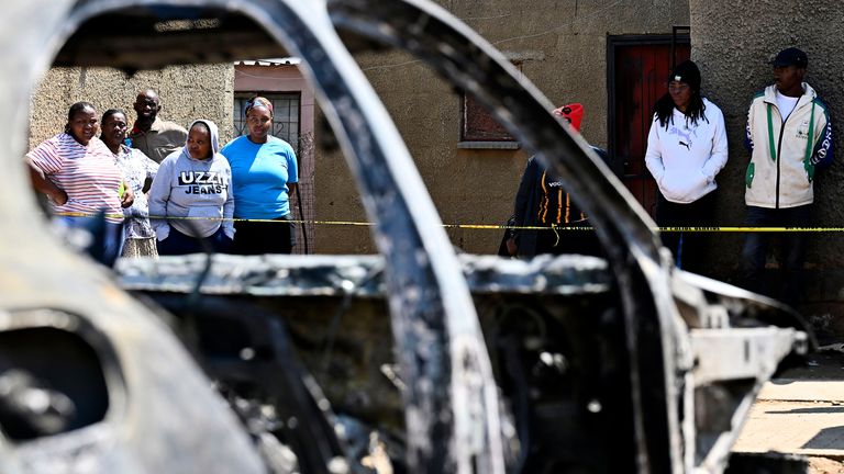 Community members stand at scene of a mass shooting on Saturday night when suspects opened fire at a bar in Wedela township. Pic: AP