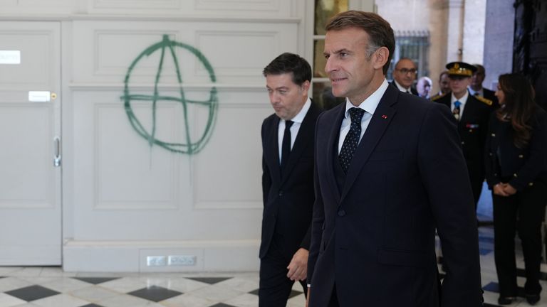 Graffiti was visible as Emmanuel Macron and Marseille's mayor entered city hall on Monday. Pic: AP